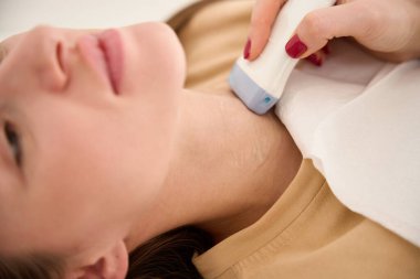 Kadın doktorun klinikteki genç beyaz kadının tiroid bezini ultrasonla tararken ki kısmi görüntüsünü kapat. Sağlık hizmetleri kavramı