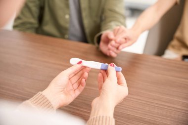 Bulanık klinikte muayene sırasında kadın jinekoloğun ve el ele tutuşan çiftin ellerindeki hamilelik testini kapat. Hamilelik ve babalık kavramı