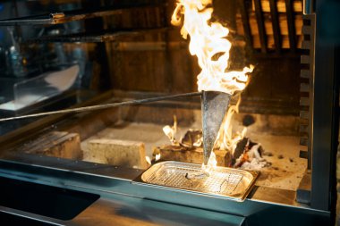 Lokantadaki şöminede demir tepside istiridye kızartmak için kullanılan flambe tekniği. Lezzetli sağlıklı yemek kavramı