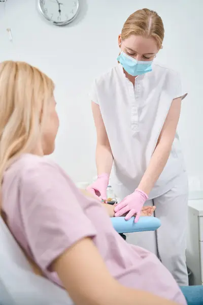 stock image Female client of aesthetic medicine clinic donating blood sample to health check-up before treatment and recreating in medical centre