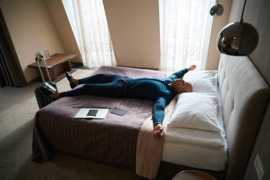 Yorgun Afrikalı Amerikalı iş adamı gündüzleri otel odasında yatıp dinleniyor. İş gezisi, dinlenme, tatil ve seyahat kavramı