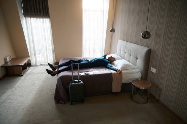 Yorgun Afrikalı Amerikalı erkek girişimci gündüzleri otel odasında yatakta uyuyor. İş gezisi, dinlenme, tatil ve seyahat kavramı