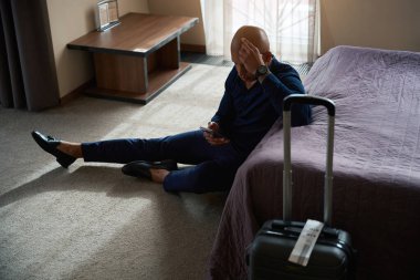 Afrika kökenli Amerikalı işadamı gündüzleri otel odasında cep telefonunu kullanıyordu. İş gezisi, tatil ve seyahat kavramı