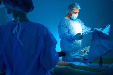 Doktor estetik ameliyata hazırlanıyor. Hastanedeki ameliyat odasında steril ekipmanları kontrol ediyor.