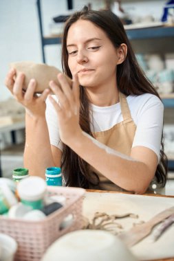 Potter denen kadın seramik atölyesinde el yapımı kil kaseyi elinde tutuyor.
