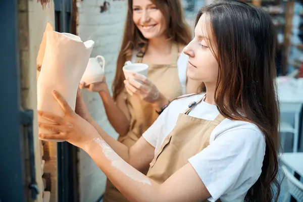 stock image Professional women potters placing clay ceramics mugs kiln in pottery workshop