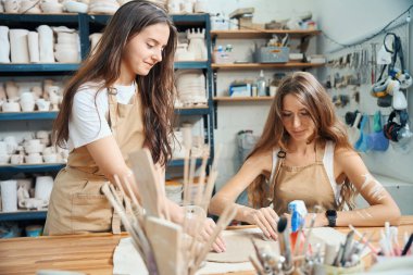 Çömlek ürünlerini atölyede modellemek için kilden hamurla çalışan kadın çömlekçiler