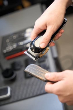 Çağdaş berber dükkanında saç kesme makinesi ve fırça tutan berberin yakın görüntüsü