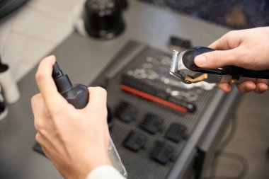 Kuaförde temizlik spreyi sıkarak Kafkasyalı berberin saç makası temizleme görüntüsü
