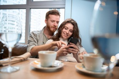 Bir çift restoranda randevudayken telefona bakıyor.