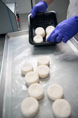 Yarı bitmiş ürün atölyesinin çalışanı, tek kullanımlık ambalaj kullanarak müşteriye teslim etmek üzere süzme peynirli krep paketliyor.