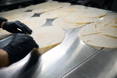 Büyük masada çalışan kadın ve müşteriye teslim için börek hazırlıyorum.