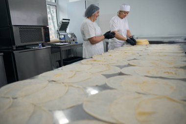 Mutfak çalışanları krep hazırlar, büyük bir masada çalışırlar.