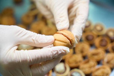 Nitelikli fırıncı, içi dolgulu tatlı fındık dilimlerini birbirine bastırıyor, kurabiyeleri konsantre süt veya çikolatalı şekerle hazırlıyor, özel fırın