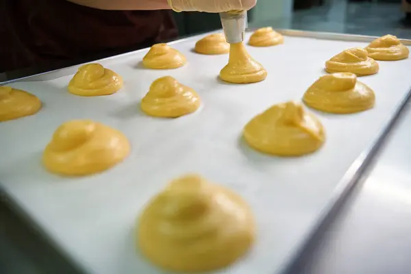 Stock image Pretty circles from pastry dough lying on baking paper on the baking sheet, professional confectioner going to bake profiteroles