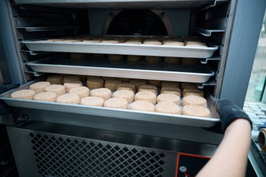 Atölye çalışanı buzdolabına pirzola koyuyor, atölyede modern ekipmanlar var.