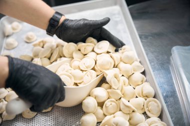 Shop worker packs frozen dumplings into a bag for delivery to a client clipart