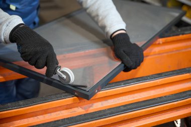 İşçi, cam fabrikasında sivrisinek ağı yapıyor. Özel bir alet kullanıyor.