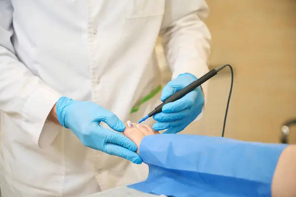 stock image Cropped photo of podiatric surgeon in lab coat and nitrile gloves removing skin lesion on client toe using electrocautery device