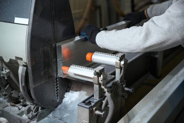 Usta özel bir makinede alüminyum profil ile çalışır, işçi koruyucu eldiven giyer.