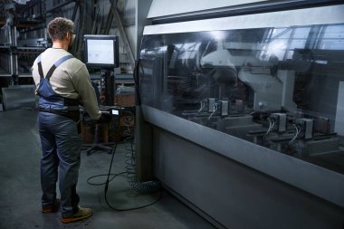 Uzman, bir üretim atölyesinde modern bir bilgisayar kullanıyor.