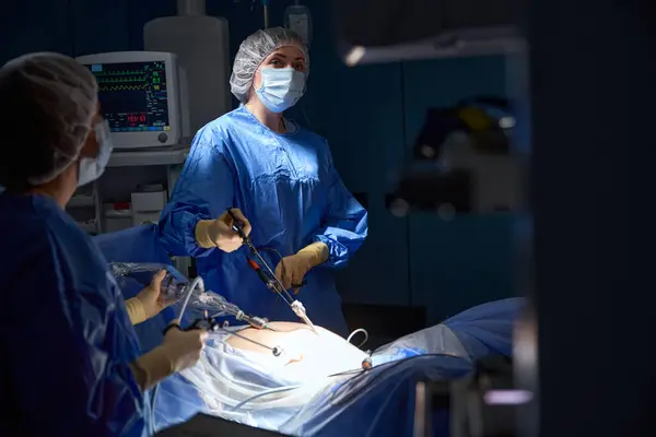 stock image Female doctors in protective uniform performing laparoscopy operations in the intensive care unit. Laparoscopy in surgery