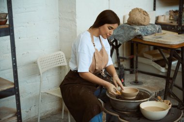 Kadın çömlekçi, yaratıcı sanat alanında, profesyonel stüdyoda çömlek çarkında kille çalışıyor. El işi seramik çömlek üretimi