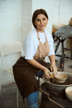Seramik stüdyosunda el yapımı çömlek dükkanı için el işi kavanozu üretiminde genç bir bayan. El işi seramik çömlek üretimi