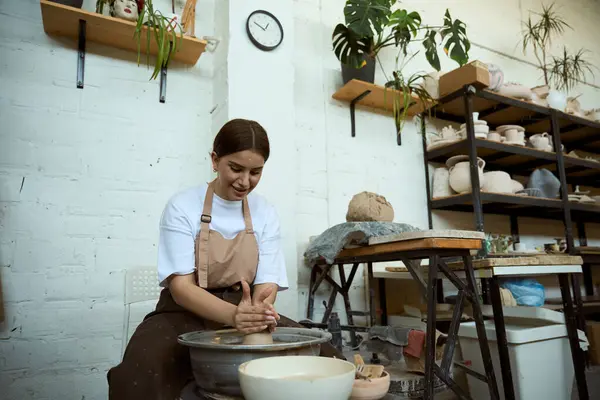 Çömlekçi çarkında seramik demlik yapan gülümseyen genç kadın. El işi seramik çömlek üretimi