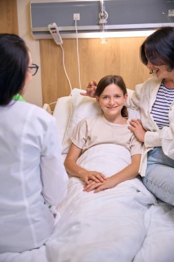 Şefkatli anne, hasta kızını nazikçe kucaklıyor.