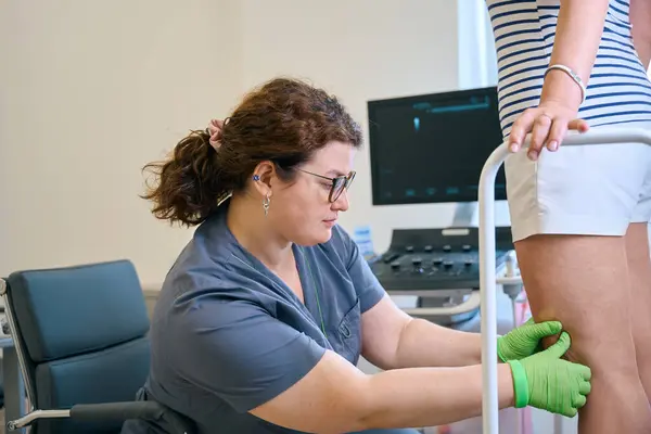 stock image Female phlebologist examines the legs of a patient, next to a modern ultrasound machine