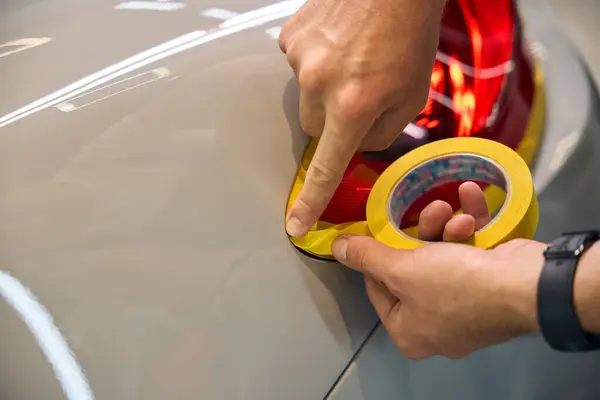 stock image Guy puts a protective film on a headlight during the detailing process, he has a smart watch on his hand