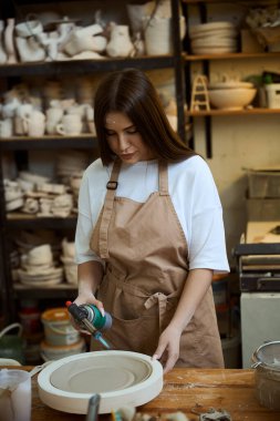 Bir atölyede el yapımı önlük seramiğinin kadın ustası bulaşık yapıyor. Çömlek oluşturma süreci