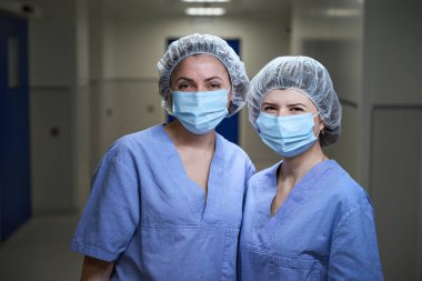 Tıbbi koruyucu giysiler giyen kadın doktorlar sanat kamerasına bakıyor. Sağlık ve Tıp Konsepti