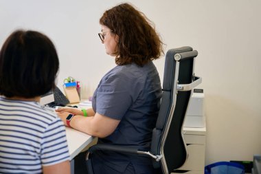 Damar uzmanı klinikten randevu alır, kadınlar parlak bir ofiste iletişim kurar.