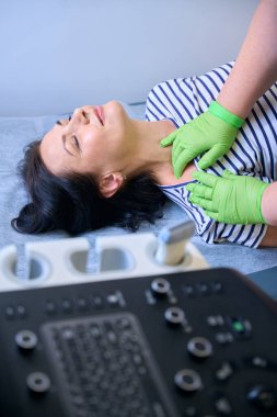 İş yerindeki ev doktoru hastaların lenf düğümlerini kontrol ediyor, kadın kanepede yatıyor.