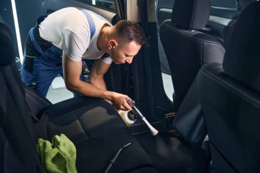 İşçi, otomatik temizleme yaparken bir tornador ile arabanın içini iyice temizler.