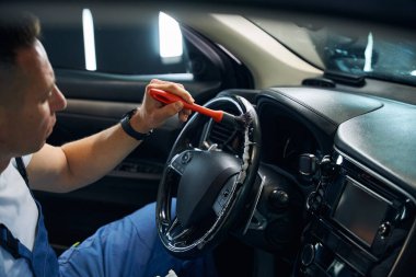 Adam özel bir fırça kullanarak direksiyon simidini temizliyor.