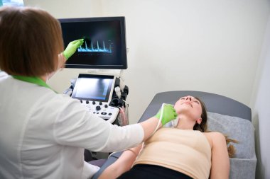 Kafkasyalı kadın hasta muayene sırasında doktor odasında kanepede yatıyor.