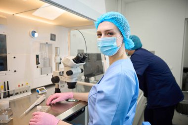 Mavi laboratuvar önlüklü ve eldivenli doktor laboratuvar aletlerini kontrol edilen ortamda hassas bir prosedür için ayarlar.