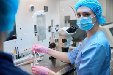 Tam donanımlı bir laboratuvardaki doktor, steril bir ortamda katı protokolleri takip ederken hassas alet ve numunelerle ilgilenir..