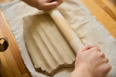 Usta ahşap bir oklava ile bir katman kil atar, her şey iş yerinde düzenlenir.