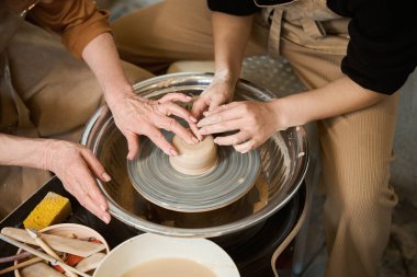 Kadınlara çanak çömlek üzerinde çalışmayı öğreten usta, stüdyoda çömlekçilik dersi alan bayan.