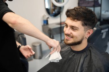 Profesyonel stilist, müşterinin yanında duruyor, büyük fırça tutuyor ve ekmeğin üzerine beyaz toz sürüyor.