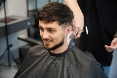 Profesyonel stilist, müşterinin yanında duruyor, büyük fırça tutuyor ve saç kesiminden sonra pudra sürüyor.