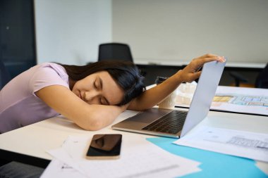 Kadın iş yerinde uyuyakalmış, çok fazla çalışmaktan yorulmuş.