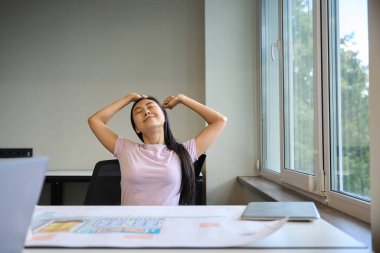 Kadın ofis sandalyesinde tatlı tatlı gerinir, çok fazla çalışmaktan yorgun düşer.