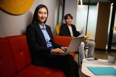 Meslektaşlar ortak çalışma alanındadırlar, standart ofis elbiselerindedirler.