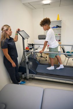 Profesyonel fizyoterapist hastaya koşu bandı eğitiminde destek sağlayarak, güvenlik ve doğru duruş sağlanmasına yardımcı olur.