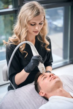 Deri yenileme ve doku geliştirme ünüyle tanınan, estetik tıp kliniğindeki yüksek nitelikli güzellik uzmanını ziyaret eden adam, mikroskobik rf kaldırmayı deniyor.